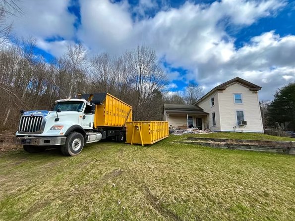 A Carl's Dumpsters roll-off dumpster filled with remodeling debris beside a house